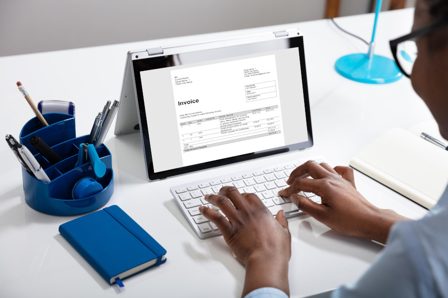 Businesswoman Using Laptop Preparing Invoice